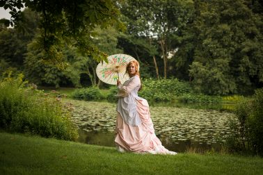 Schloss Borbeck - Frau in rosa Tournürenkleid vor Teich